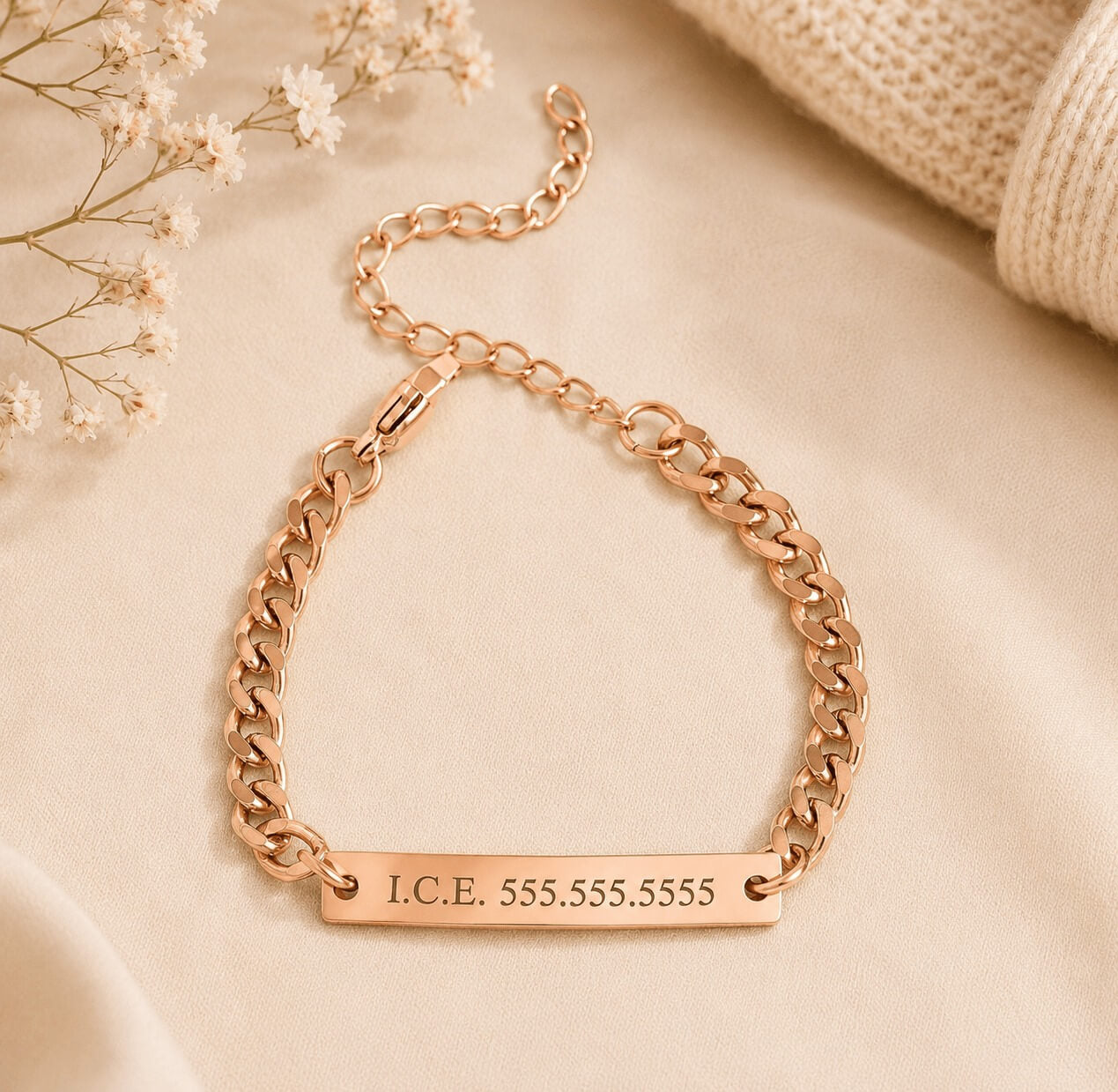 Rose gold chain bracelet with engraved text on a beige fabric background