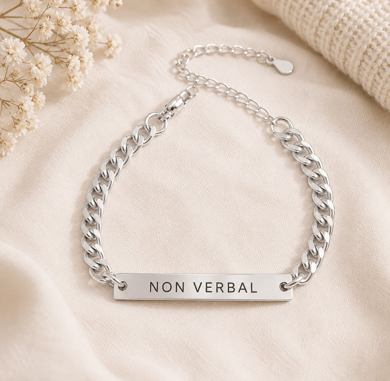 Silver chain bracelet with 'NON VERBAL' tag on a beige fabric background